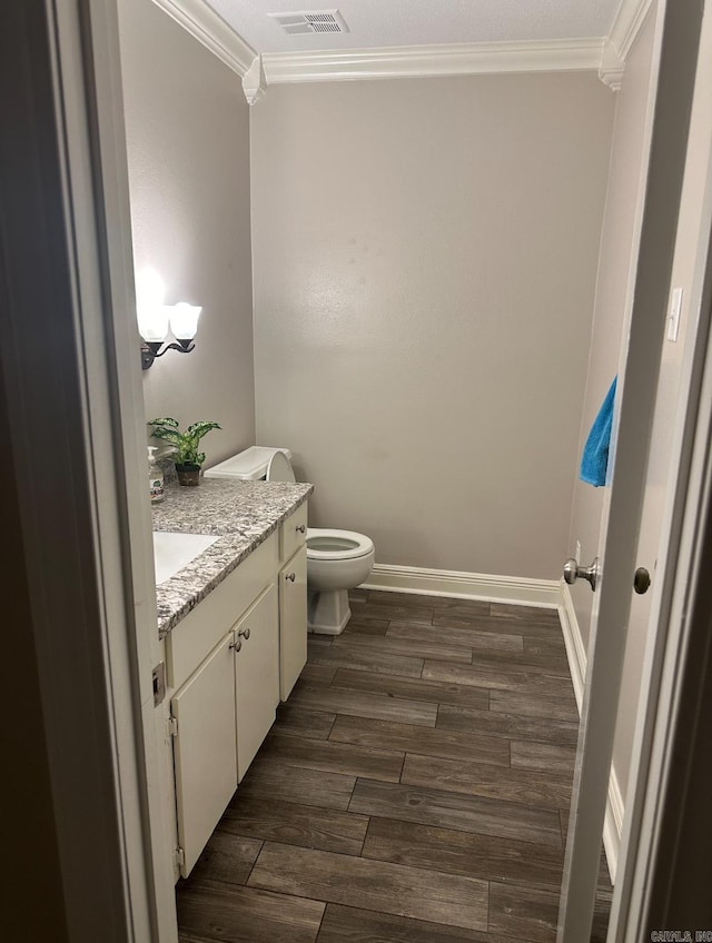 bathroom with crown molding, vanity, toilet, and wood-type flooring