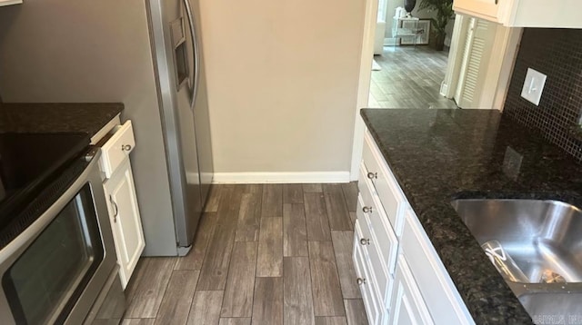 kitchen with stainless steel range oven, dark stone countertops, white cabinetry, and dark wood-type flooring