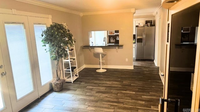 interior space with a breakfast bar area, dark hardwood / wood-style floors, stainless steel refrigerator with ice dispenser, ornamental molding, and white cabinets