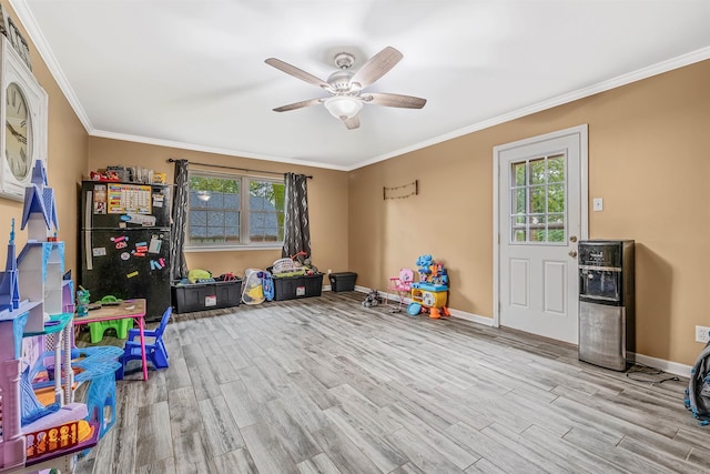 playroom featuring ceiling fan, plenty of natural light, ornamental molding, and light hardwood / wood-style flooring