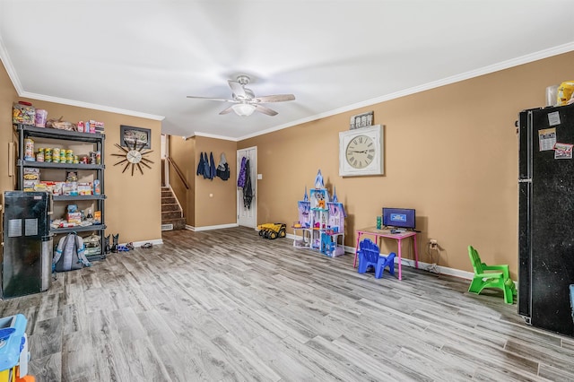 recreation room with ceiling fan, ornamental molding, and light hardwood / wood-style floors