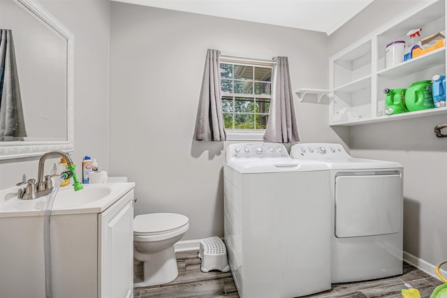 clothes washing area with hardwood / wood-style flooring, independent washer and dryer, and sink