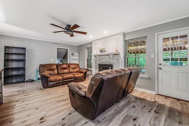 living room featuring ornamental molding, a brick fireplace, ceiling fan, and light hardwood / wood-style floors