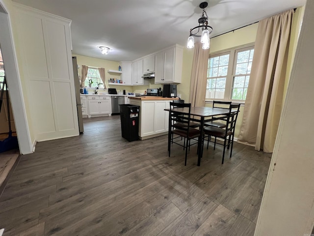 kitchen featuring decorative light fixtures, white cabinets, butcher block counters, and a healthy amount of sunlight