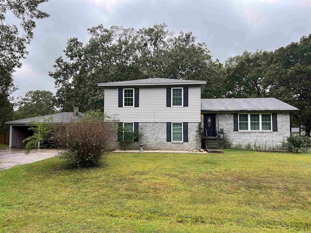 split level home featuring driveway, brick siding, a carport, and a front yard