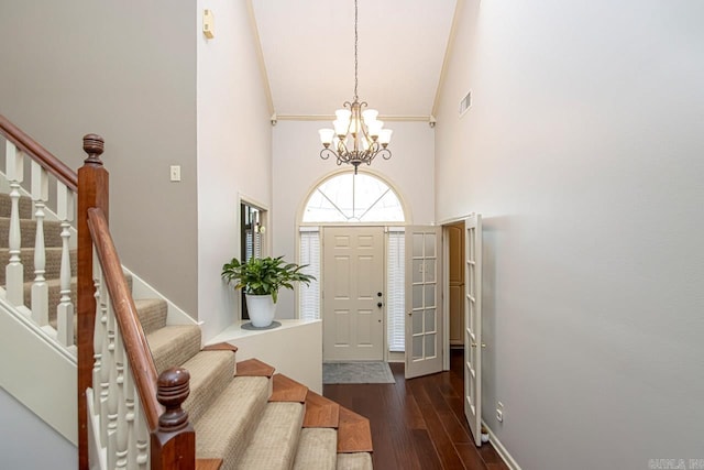 foyer entrance with crown molding, dark hardwood / wood-style floors, high vaulted ceiling, and a notable chandelier