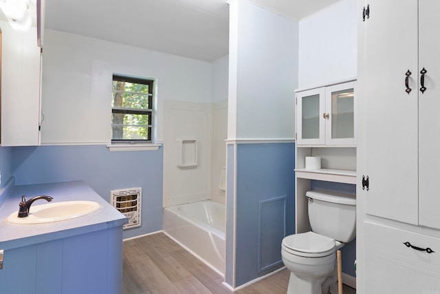 full bathroom featuring toilet, plus walk in shower, vanity, wood-type flooring, and heating unit