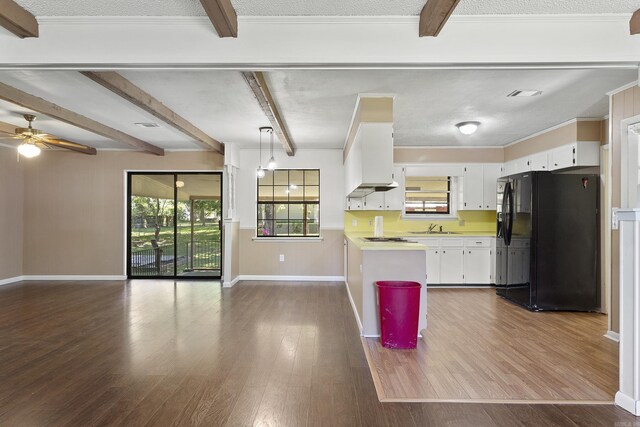 kitchen with a textured ceiling, pendant lighting, black fridge, and white cabinetry