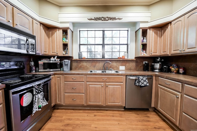 kitchen with light wood-type flooring, crown molding, sink, decorative backsplash, and appliances with stainless steel finishes