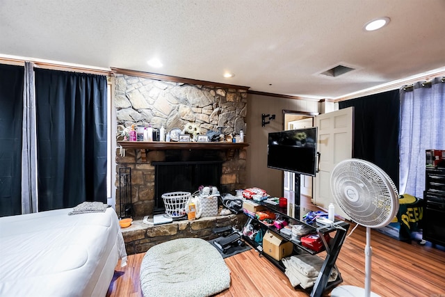 living room with a fireplace, ornamental molding, hardwood / wood-style floors, and a textured ceiling