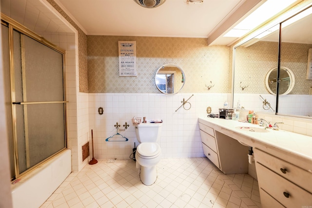 full bathroom featuring tile walls, toilet, bath / shower combo with glass door, and vanity