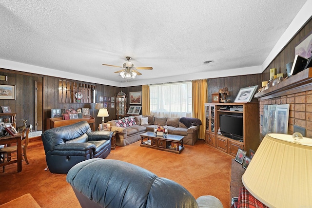 carpeted living room with a textured ceiling, wooden walls, and ceiling fan