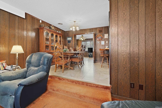 living area with light tile patterned floors, a notable chandelier, wood walls, and a textured ceiling