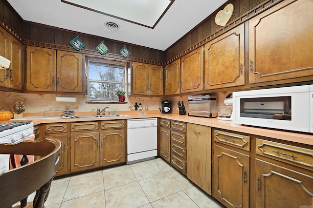 kitchen with light tile patterned flooring, light countertops, visible vents, and white appliances