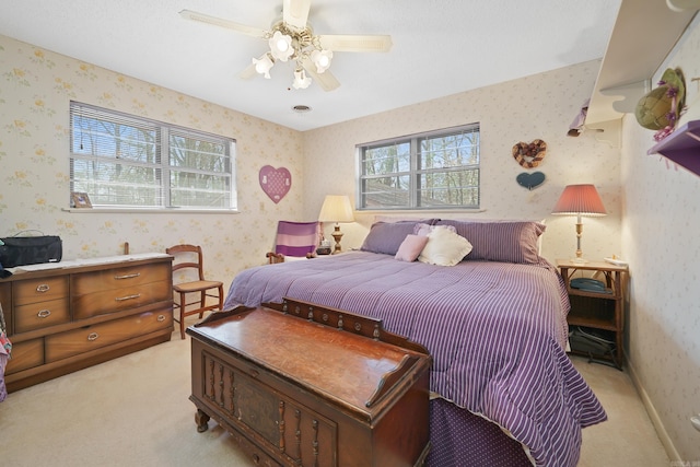 bedroom with light colored carpet, wallpapered walls, ceiling fan, and baseboards