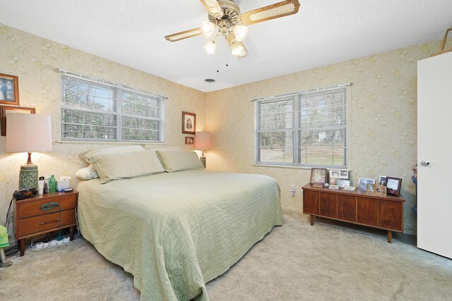 carpeted bedroom with a textured ceiling, a textured wall, and a ceiling fan
