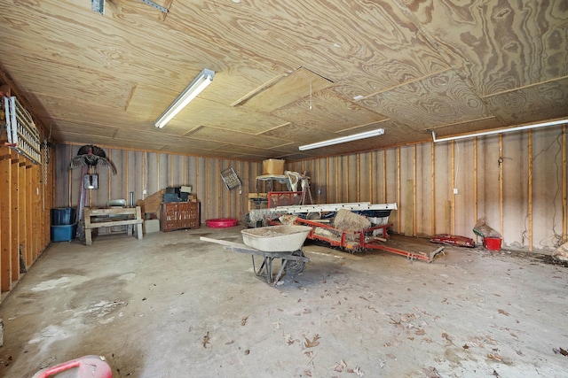miscellaneous room featuring unfinished concrete floors, attic access, and a garage