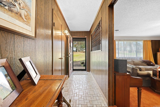 entryway featuring stone finish floor, visible vents, wood walls, and a textured ceiling