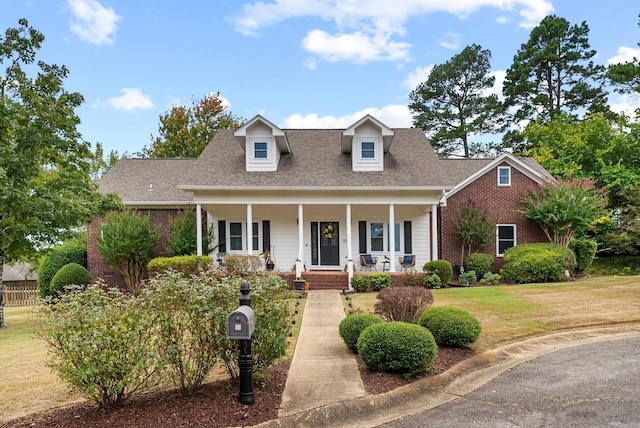 cape cod-style house with a front yard and covered porch