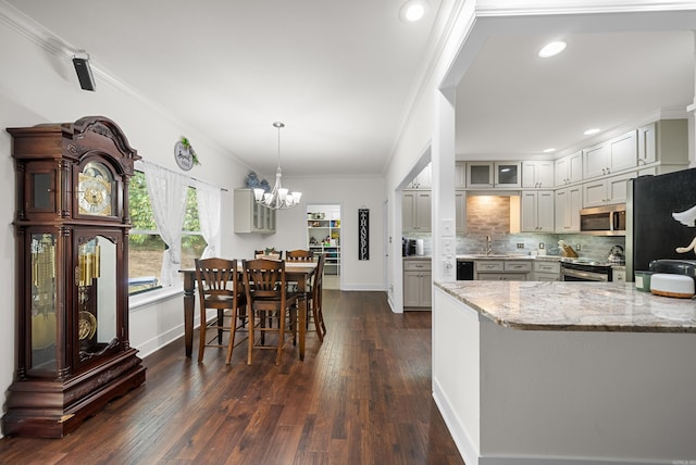 kitchen featuring appliances with stainless steel finishes, a chandelier, dark hardwood / wood-style floors, kitchen peninsula, and pendant lighting