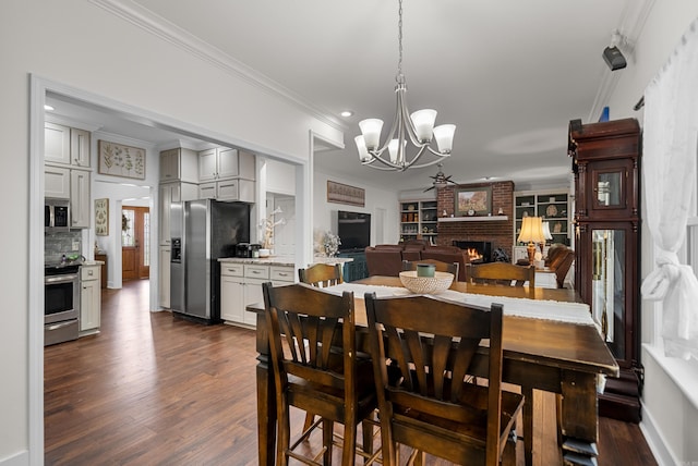 dining room with dark wood-type flooring, a fireplace, a chandelier, and ornamental molding