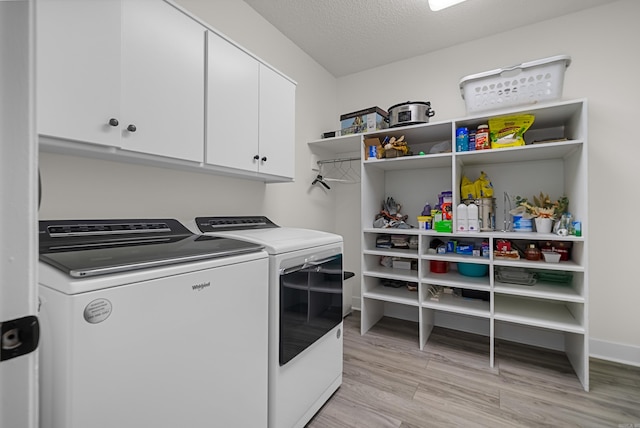 washroom with light wood-type flooring, cabinets, washer and clothes dryer, and a textured ceiling