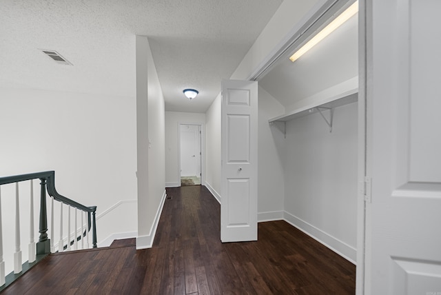 corridor with dark hardwood / wood-style flooring and a textured ceiling