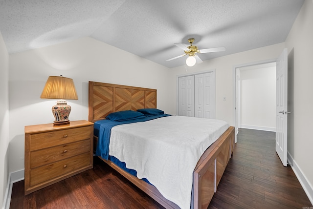 bedroom featuring a textured ceiling, a closet, dark wood-type flooring, lofted ceiling, and ceiling fan