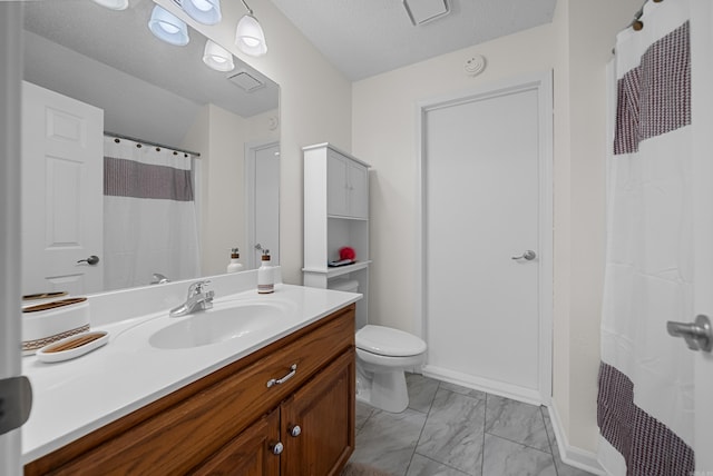 bathroom with vanity, toilet, and a textured ceiling