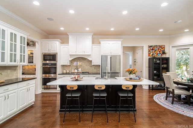 kitchen with appliances with stainless steel finishes, white cabinetry, and a large island with sink