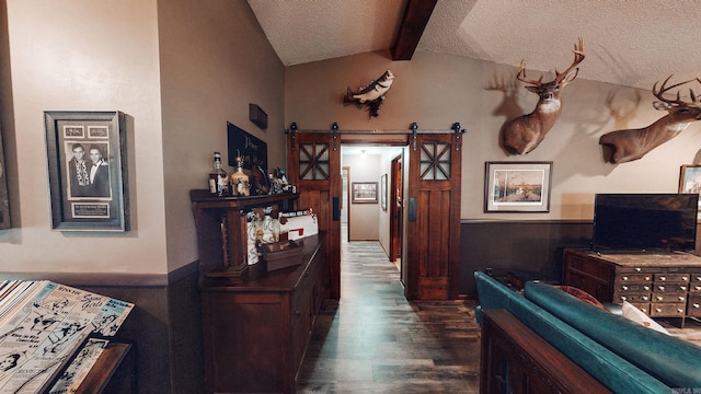 hallway with a textured ceiling, dark hardwood / wood-style flooring, a barn door, and vaulted ceiling with beams