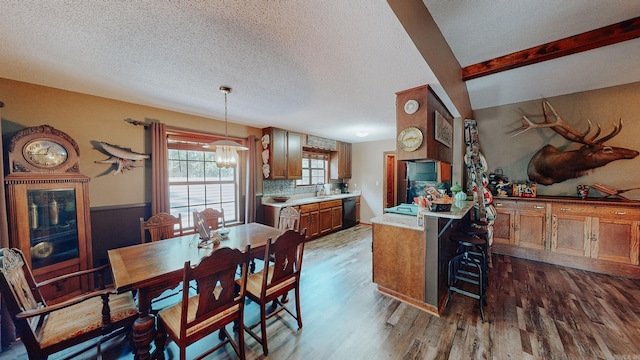 dining space with sink, dark wood-type flooring, beam ceiling, a textured ceiling, and an inviting chandelier