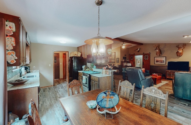 dining space featuring sink, light wood-type flooring, lofted ceiling with beams, a textured ceiling, and a chandelier