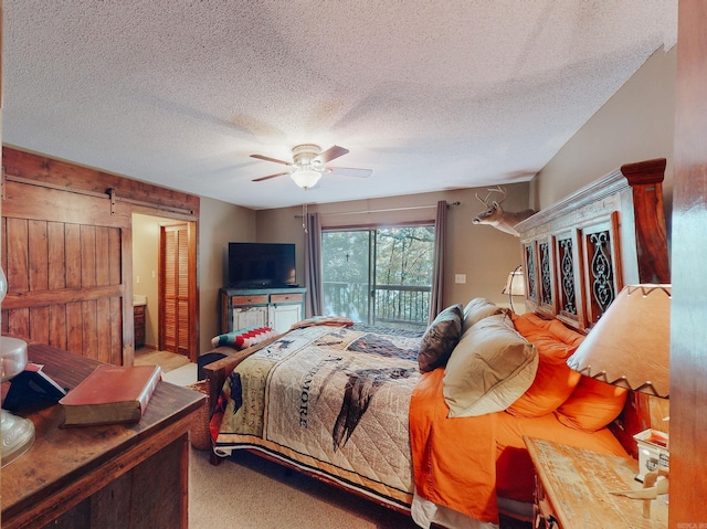 carpeted bedroom featuring a textured ceiling, access to exterior, ceiling fan, and a barn door