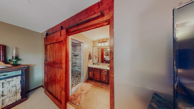 corridor featuring a barn door, light tile patterned floors, and a textured ceiling