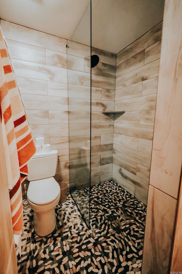 bathroom featuring toilet and a tile shower