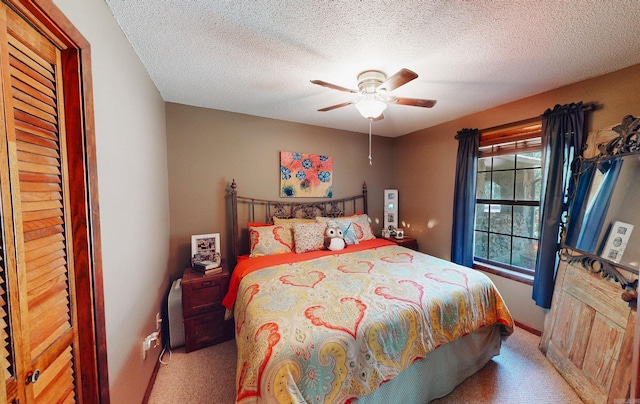 bedroom with ceiling fan, light colored carpet, and a textured ceiling