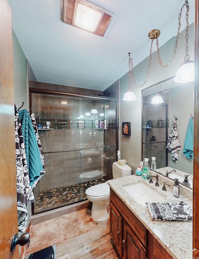 bathroom with hardwood / wood-style flooring, a shower with door, toilet, and vanity