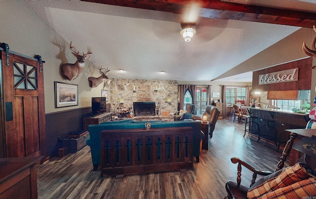 living room with wood-type flooring, a fireplace, vaulted ceiling, and a barn door