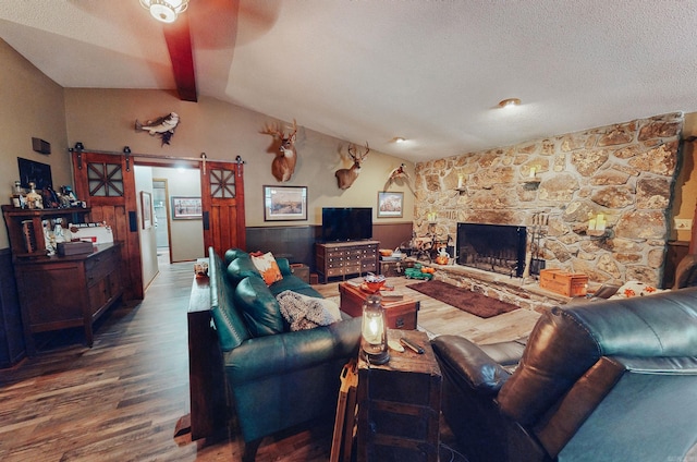 living room featuring a barn door, a textured ceiling, dark hardwood / wood-style flooring, and lofted ceiling with beams