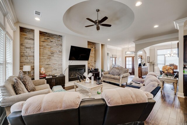 living room with ceiling fan with notable chandelier, dark hardwood / wood-style floors, ornate columns, and a wealth of natural light