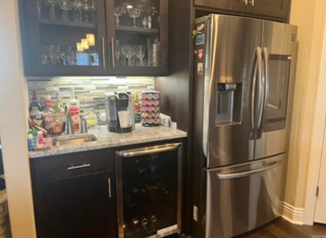 interior space featuring light stone counters, stainless steel fridge, dark brown cabinets, beverage cooler, and dark hardwood / wood-style floors