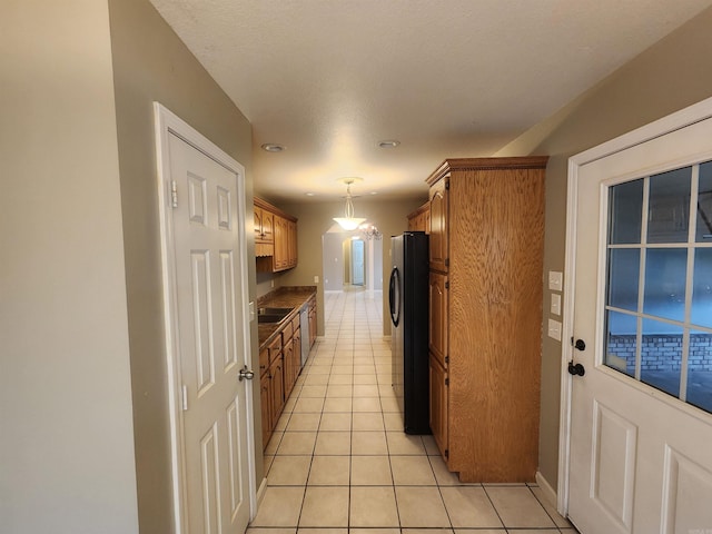 kitchen with a textured ceiling, appliances with stainless steel finishes, light tile patterned flooring, and decorative light fixtures