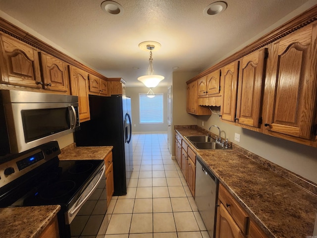 kitchen featuring light tile patterned flooring, stainless steel appliances, a textured ceiling, pendant lighting, and sink