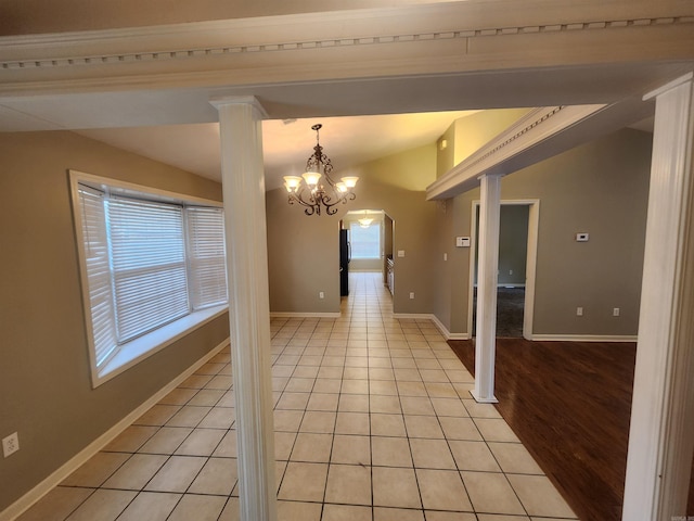 unfurnished dining area featuring light hardwood / wood-style floors, a notable chandelier, lofted ceiling, and decorative columns