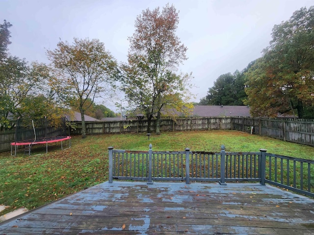 wooden deck with a yard and a trampoline