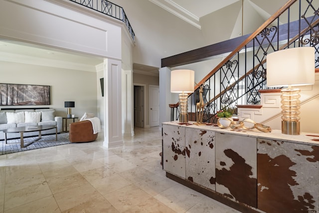 foyer entrance with ornamental molding and a towering ceiling