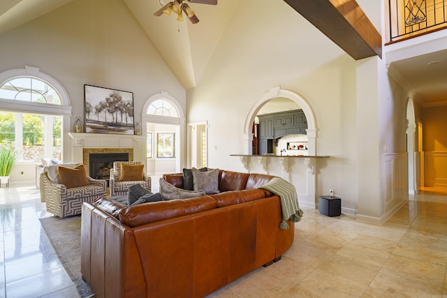 living room with a tiled fireplace, high vaulted ceiling, and ceiling fan