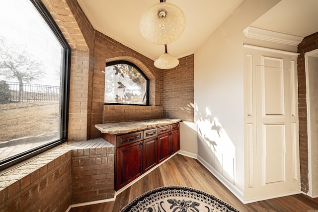 interior space featuring brick wall, pendant lighting, and light hardwood / wood-style floors