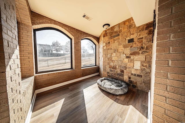 interior space featuring brick wall and hardwood / wood-style floors